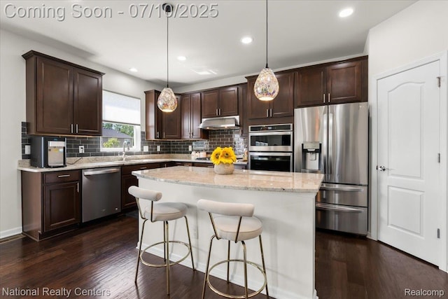 28049 Hummingdale Cir, Novi, MI 48377 - kitchen with stainless steel appliances, under cabinet range hood, dark brown cabinets, backsplash, and a center island
