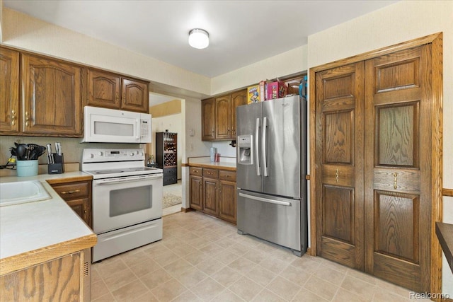 42109 Hartford Dr, Canton, MI 48187 - kitchen with white appliances, light countertops, and brown cabinetry