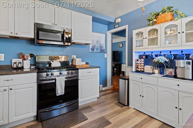 1946 Carlysle St, Dearborn, MI 48124 - kitchen with stainless steel appliances, white cabinetry, light wood finished floors, glass insert cabinets, and dark countertops