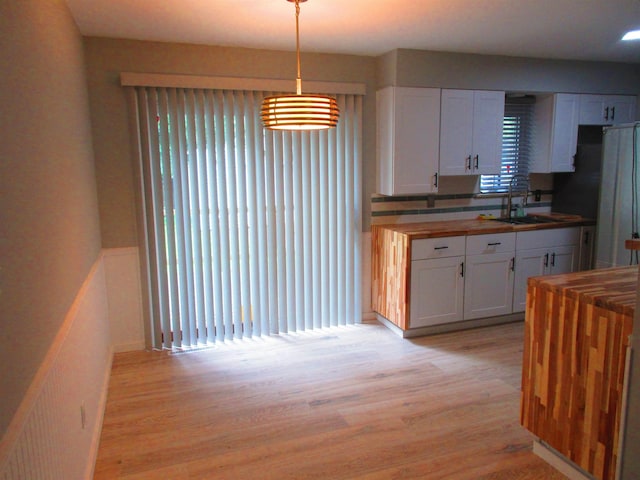 3736 Maryland Ave, Flint, MI 48506 - kitchen featuring wood counters, white cabinetry, light wood-style flooring, and decorative light fixtures
