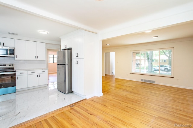 23461 Avon Rd, Oak Park, MI 48237 - kitchen with freestanding refrigerator, stainless steel microwave, electric range, decorative backsplash, and white cabinets