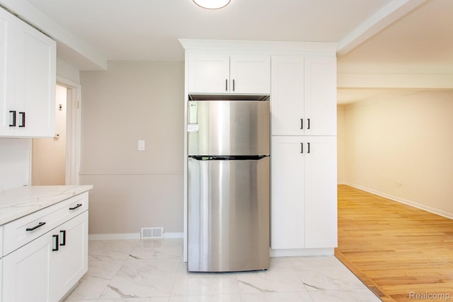 23461 Avon Rd, Oak Park, MI 48237 - kitchen with freestanding refrigerator, light stone countertops, white cabinets, and light marble finish floors