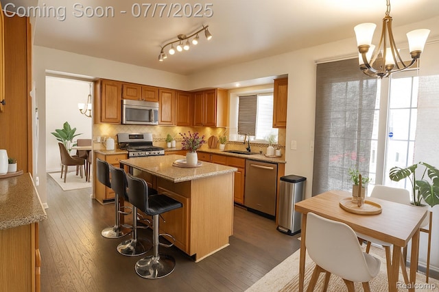 45587 Hanford Rd, Canton, MI 48187 - kitchen with appliances with stainless steel finishes, a chandelier, a center island, backsplash, and brown cabinetry