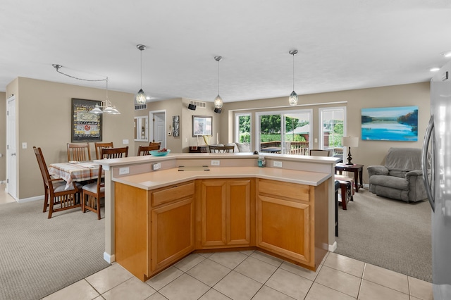 8181 Fawn Meadow Trl, Galesburg, MI 49053 - kitchen featuring light colored carpet, light countertops, open floor plan, freestanding refrigerator, and pendant lighting
