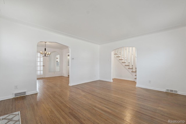 19340 Appoline St, Detroit, MI 48235 - empty room featuring wood-type flooring, a chandelier, arched walkways, and stairs