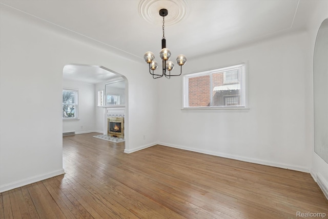 19340 Appoline St, Detroit, MI 48235 - unfurnished living room featuring light wood finished floors, a chandelier, a high end fireplace, and arched walkways