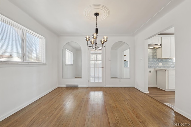 19340 Appoline St, Detroit, MI 48235 - unfurnished dining area featuring a chandelier, light wood finished floors, and arched walkways