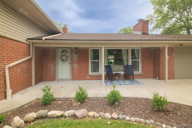 21102 Knudsen Dr, Grosse Ile, MI 48138 - property entrance featuring a chimney, brick siding, an attached garage, and covered porch