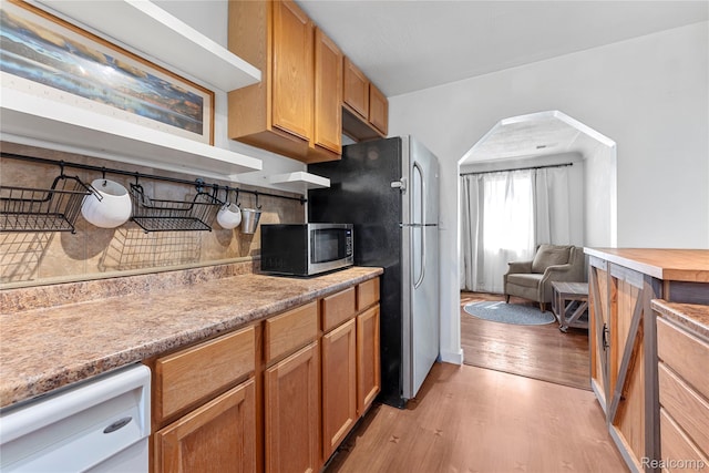 6917 Belton St, Garden City, MI 48135 - kitchen featuring appliances with stainless steel finishes, light wood-type flooring, tasteful backsplash, light countertops, and arched walkways