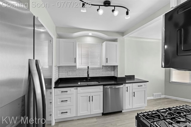 18258 Manor St, Detroit, MI 48221 - kitchen featuring stainless steel appliances, dark countertops, decorative backsplash, white cabinetry, and light wood finished floors