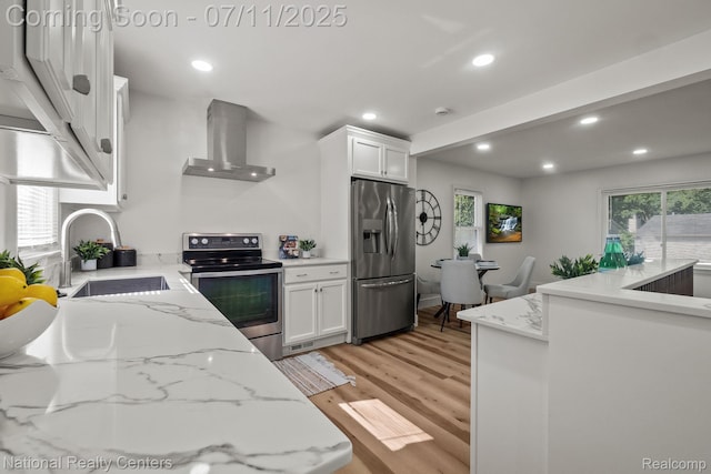 1089 Tecumseh Ave, Waterford, MI 48327 - kitchen with stainless steel appliances, wall chimney range hood, light wood-type flooring, white cabinetry, and recessed lighting