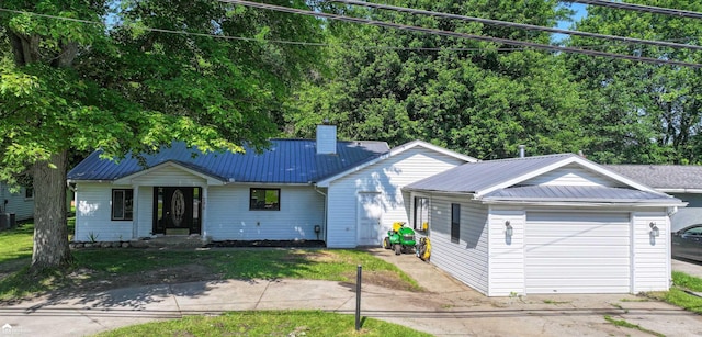 296 S Saginaw St, Montrose, MI 48457 - single story home featuring a metal roof, concrete driveway, a chimney, and a garage