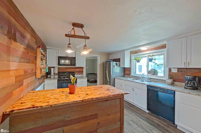 296 S Saginaw St, Montrose, MI 48457 - kitchen featuring black appliances, butcher block counters, white cabinetry, wooden walls, and a textured ceiling