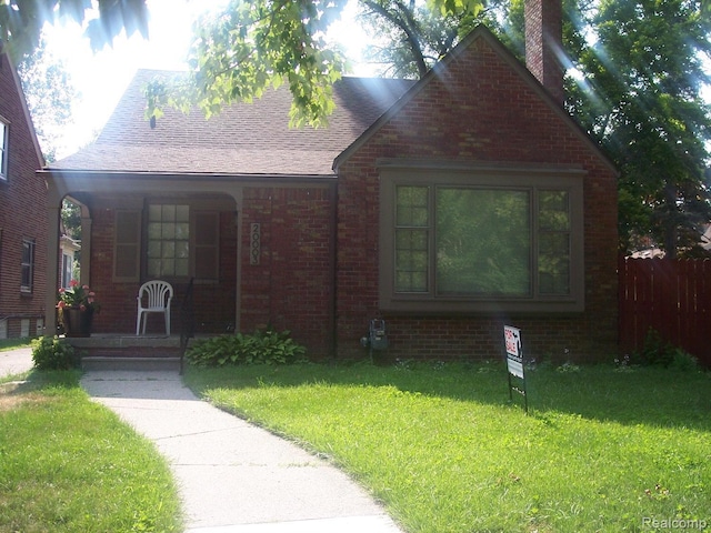 20003 Lichfield Rd, Detroit, MI 48221 - english style home featuring a porch, a front yard, brick siding, and a chimney