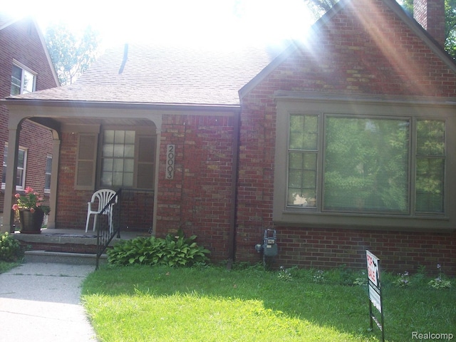 20003 Lichfield Rd, Detroit, MI 48221 - property entrance featuring a porch, brick siding, and a lawn