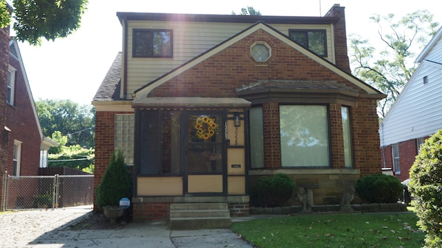 13558 Asbury Park, Detroit, MI 48227 - tudor-style house featuring brick siding, roof with shingles, and a sunroom
