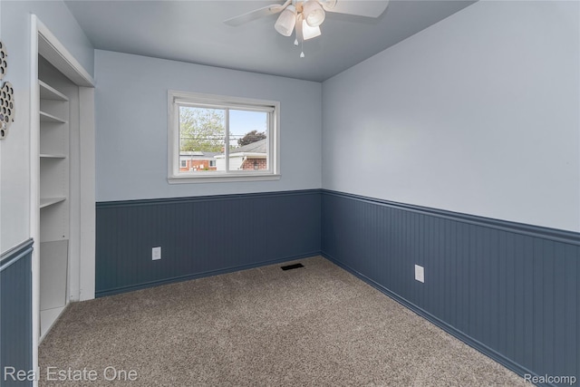 13776 Leroy St, Southgate, MI 48195 - carpeted spare room featuring a wainscoted wall, a ceiling fan, wooden walls, and built in shelves