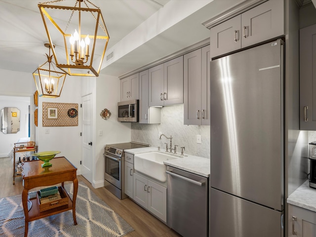 111 N Ashley St Unit 513, Ann Arbor, MI 48104 - kitchen with appliances with stainless steel finishes, gray cabinets, a chandelier, dark wood-style flooring, and decorative backsplash