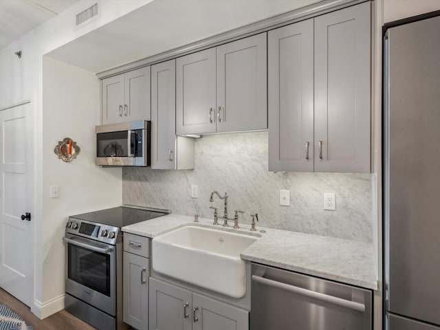 111 N Ashley St Unit 513, Ann Arbor, MI 48104 - kitchen featuring stainless steel appliances, gray cabinetry, decorative backsplash, and light stone counters