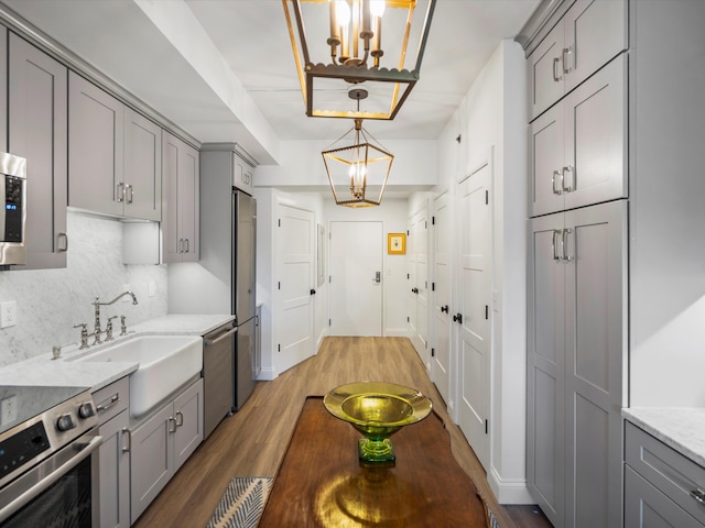 111 N Ashley St Unit 513, Ann Arbor, MI 48104 - kitchen with gray cabinetry, a chandelier, stainless steel appliances, and decorative backsplash