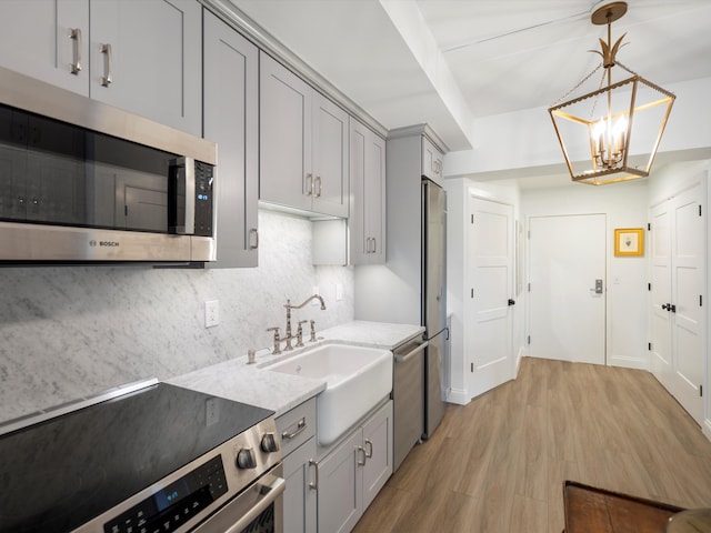 111 N Ashley St Unit 513, Ann Arbor, MI 48104 - kitchen with stainless steel appliances, gray cabinets, decorative backsplash, light wood-type flooring, and light stone counters