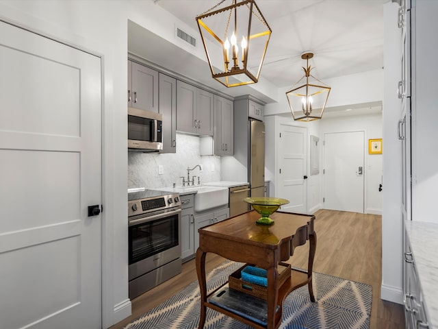 111 N Ashley St Unit 513, Ann Arbor, MI 48104 - kitchen featuring stainless steel appliances, gray cabinets, a chandelier, and backsplash