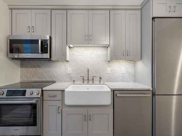 111 N Ashley St Unit 513, Ann Arbor, MI 48104 - kitchen featuring appliances with stainless steel finishes, gray cabinets, backsplash, and light stone counters