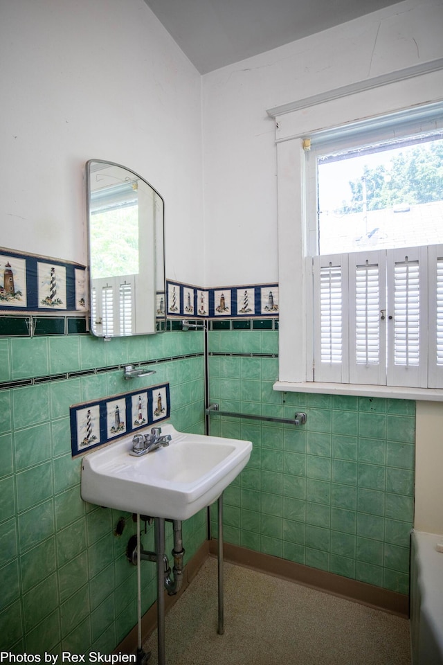 892 W Forest Ave, Muskegon, MI 49441 - bathroom featuring healthy amount of natural light, a tub, tile walls, and wainscoting