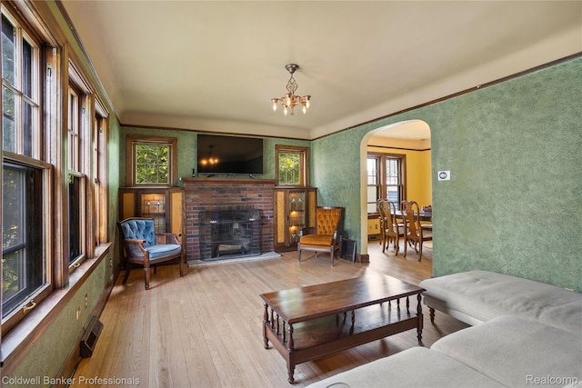 122 Linden Ct, Ypsilanti, MI 48197 - living room with arched walkways, hardwood / wood-style floors, a brick fireplace, and a chandelier