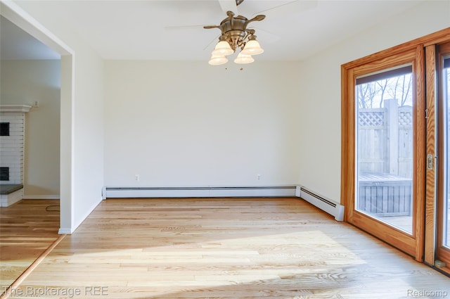 11247 Irish Rd, Otisville, MI 48463 - unfurnished room featuring light wood finished floors, ceiling fan, a brick fireplace, and baseboard heating