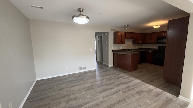 41664 Tera Ln, Novi, MI 48375 - kitchen with range, black microwave, open floor plan, dark countertops, and light wood-style floors