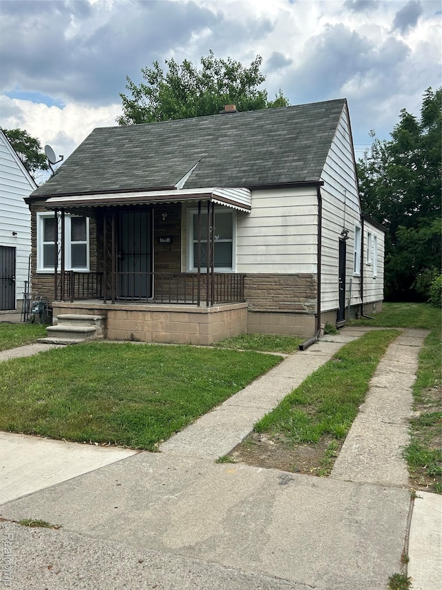 3381 S Ethel St, Detroit, MI 48217 - bungalow-style house with covered porch, a front yard, roof with shingles, and stone siding