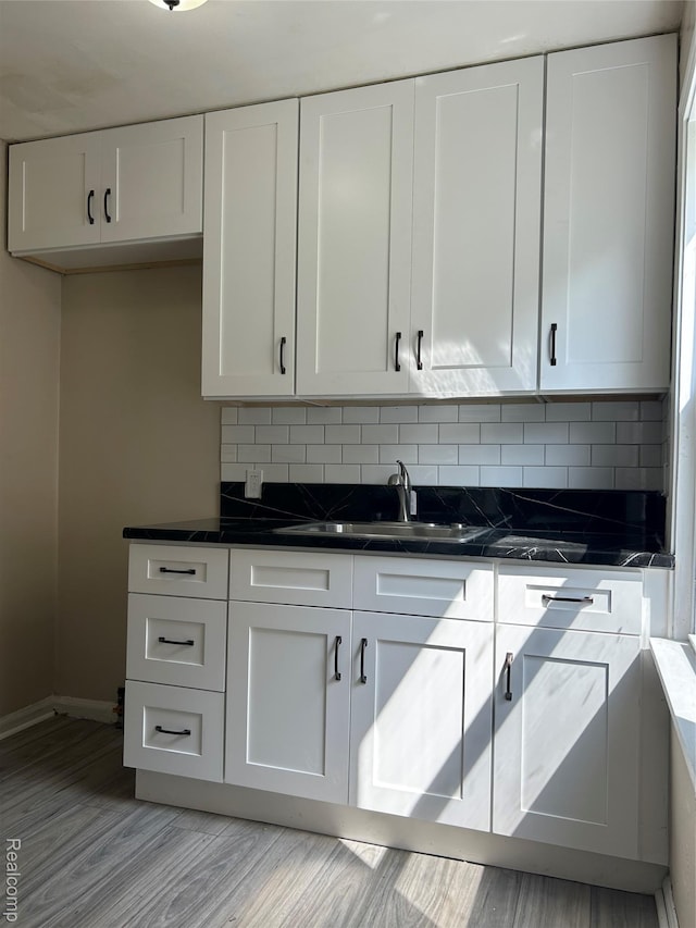 3381 S Ethel St, Detroit, MI 48217 - kitchen with dark countertops, white cabinets, backsplash, and light wood-style floors
