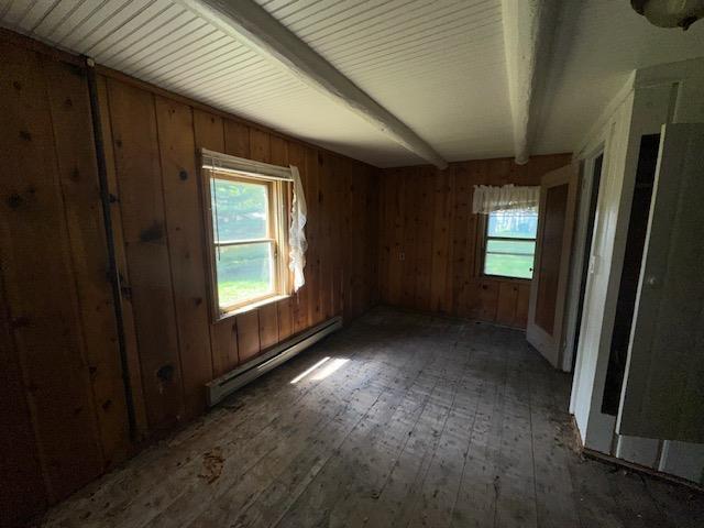 3786 W Houghton Lake Dr, Houghton Lake, MI 48629 - spare room with a baseboard radiator, hardwood / wood-style floors, plenty of natural light, wood walls, and beam ceiling