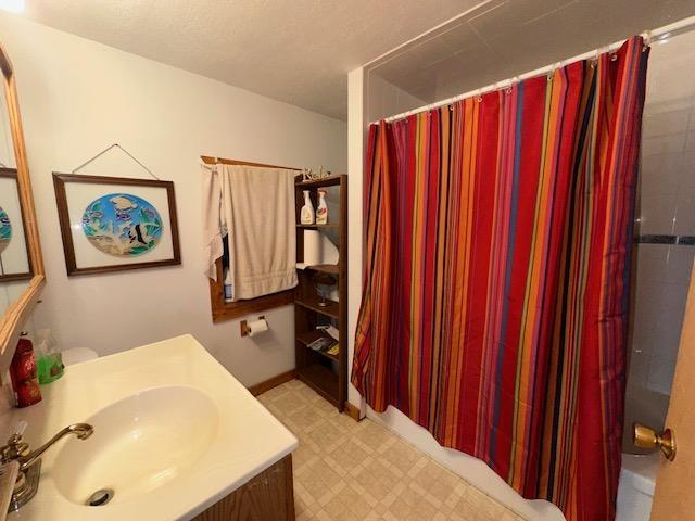 3786 W Houghton Lake Dr, Houghton Lake, MI 48629 - bathroom with tile patterned floors, vanity, and shower / tub combo