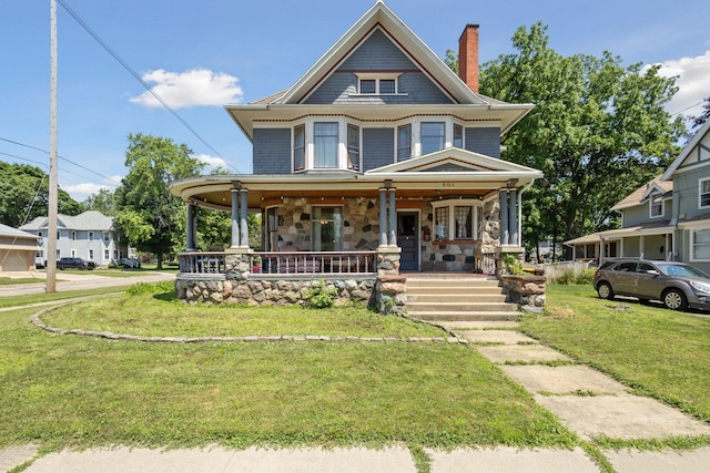 501 E Michigan Ave, Marshall, MI 49068 - victorian house with covered porch, a front yard, a chimney, and stone siding