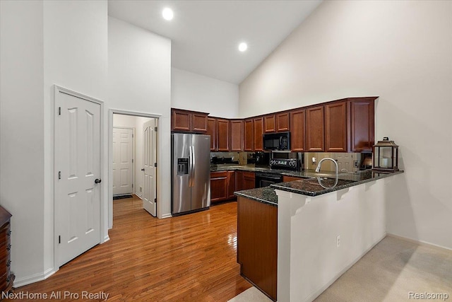 838 Knolls Landing Dr Unit 6, Milford, MI 48381 - kitchen featuring black appliances, high vaulted ceiling, a peninsula, dark stone countertops, and light wood-style floors
