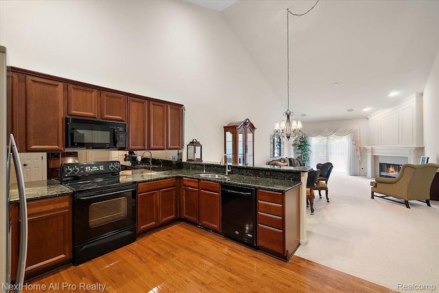 838 Knolls Landing Dr Unit 6, Milford, MI 48381 - kitchen featuring black appliances, open floor plan, a peninsula, a warm lit fireplace, and a chandelier
