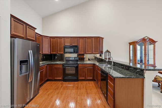 838 Knolls Landing Dr Unit 6, Milford, MI 48381 - kitchen with black appliances, high vaulted ceiling, a peninsula, dark stone countertops, and light wood-type flooring