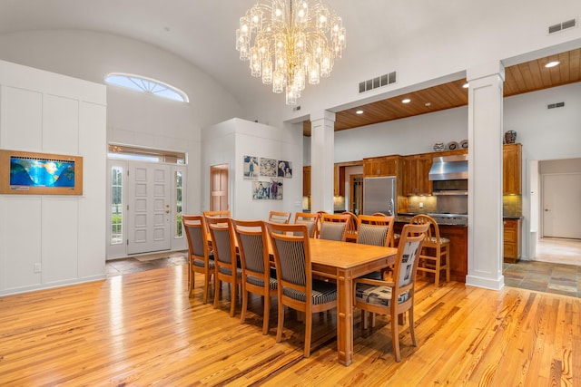 14091 Scio Church Rd, Chelsea, MI 48118 - dining area featuring ornate columns, light wood-style floors, high vaulted ceiling, and a chandelier