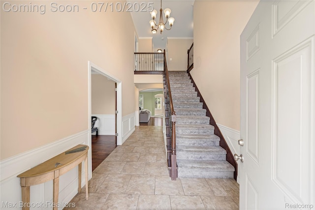 5142 Trailwood Ln, Warren, MI 48092 - stairway featuring arched walkways, a high ceiling, a wainscoted wall, a decorative wall, and a chandelier