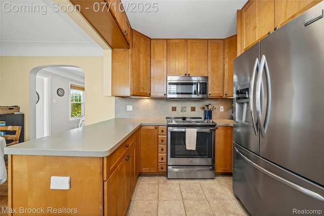 903 Oakridge Ave, Royal Oak, MI 48067 - kitchen featuring appliances with stainless steel finishes, arched walkways, tasteful backsplash, a peninsula, and brown cabinetry