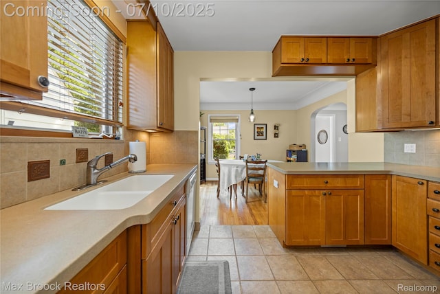 903 Oakridge Ave, Royal Oak, MI 48067 - kitchen with brown cabinetry, light countertops, backsplash, dishwashing machine, and ornamental molding