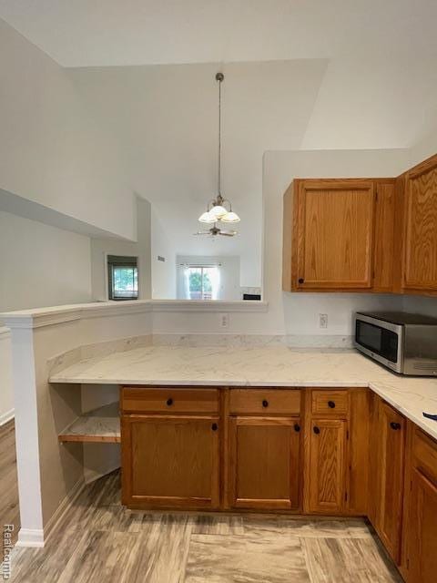 30885 Lee Frank Ln, Madison Heights, MI 48071 - kitchen with stainless steel microwave, brown cabinets, light stone countertops, and lofted ceiling