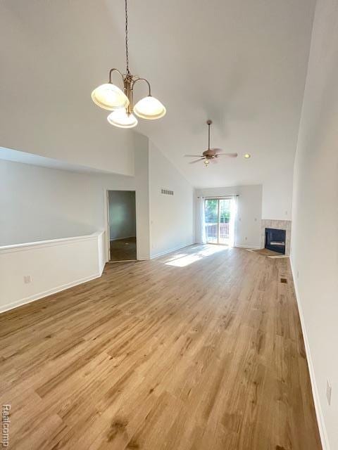 30885 Lee Frank Ln, Madison Heights, MI 48071 - unfurnished living room featuring light wood-style flooring, a tile fireplace, a chandelier, high vaulted ceiling, and a ceiling fan