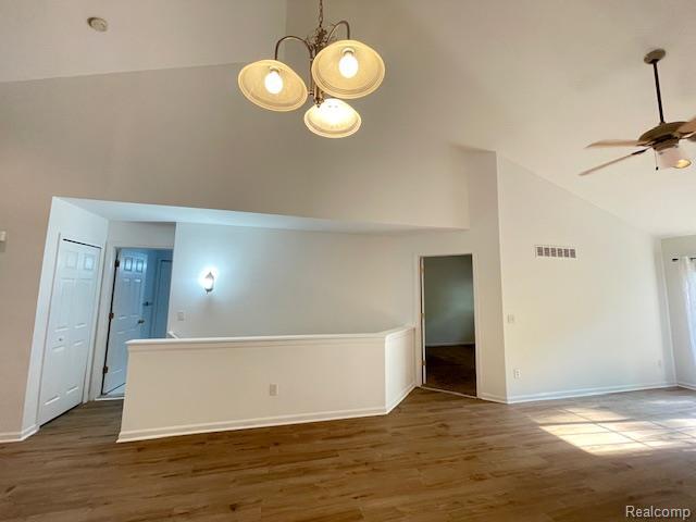 30885 Lee Frank Ln, Madison Heights, MI 48071 - empty room featuring high vaulted ceiling, a ceiling fan, wood finished floors, and a chandelier