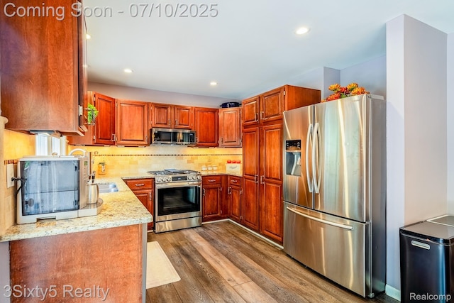 4375 Island Park Dr, Waterford, MI 48329 - kitchen featuring appliances with stainless steel finishes, wood finished floors, light stone countertops, backsplash, and brown cabinets