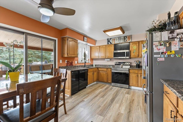 22031 Birch St, Woodhaven, MI 48183 - kitchen featuring appliances with stainless steel finishes, light wood-style flooring, a ceiling fan, brown cabinetry, and dark stone counters