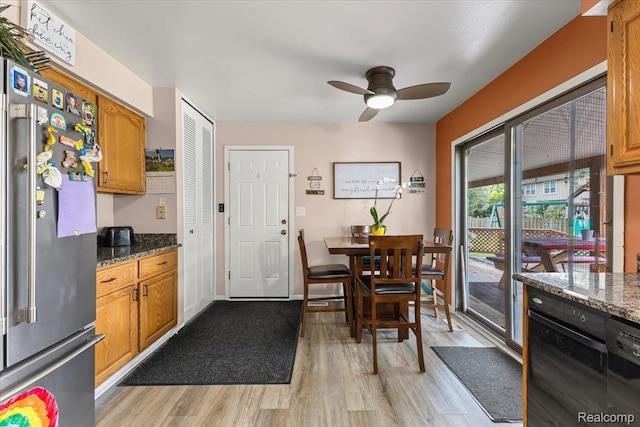 22031 Birch St, Woodhaven, MI 48183 - kitchen with freestanding refrigerator, light wood-style floors, a ceiling fan, and dark stone counters