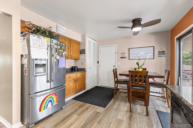 22031 Birch St, Woodhaven, MI 48183 - kitchen with stainless steel fridge, light wood finished floors, a ceiling fan, brown cabinetry, and dark stone countertops
